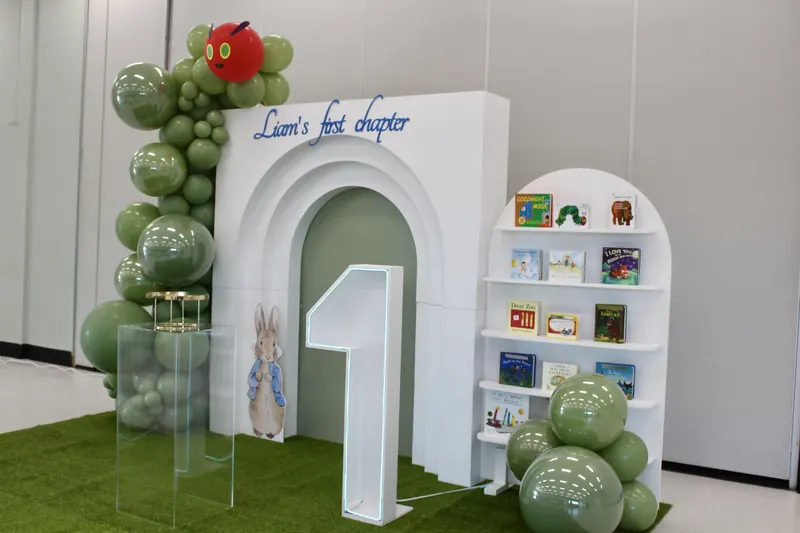 The same hall styled with balloons, arch, books and grass stage