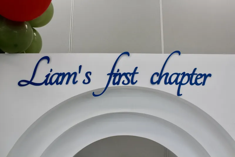 Custom blue script lettering reading Liam's first chapter above the arch